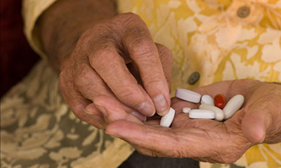 senior hand sorting through a handful of medications